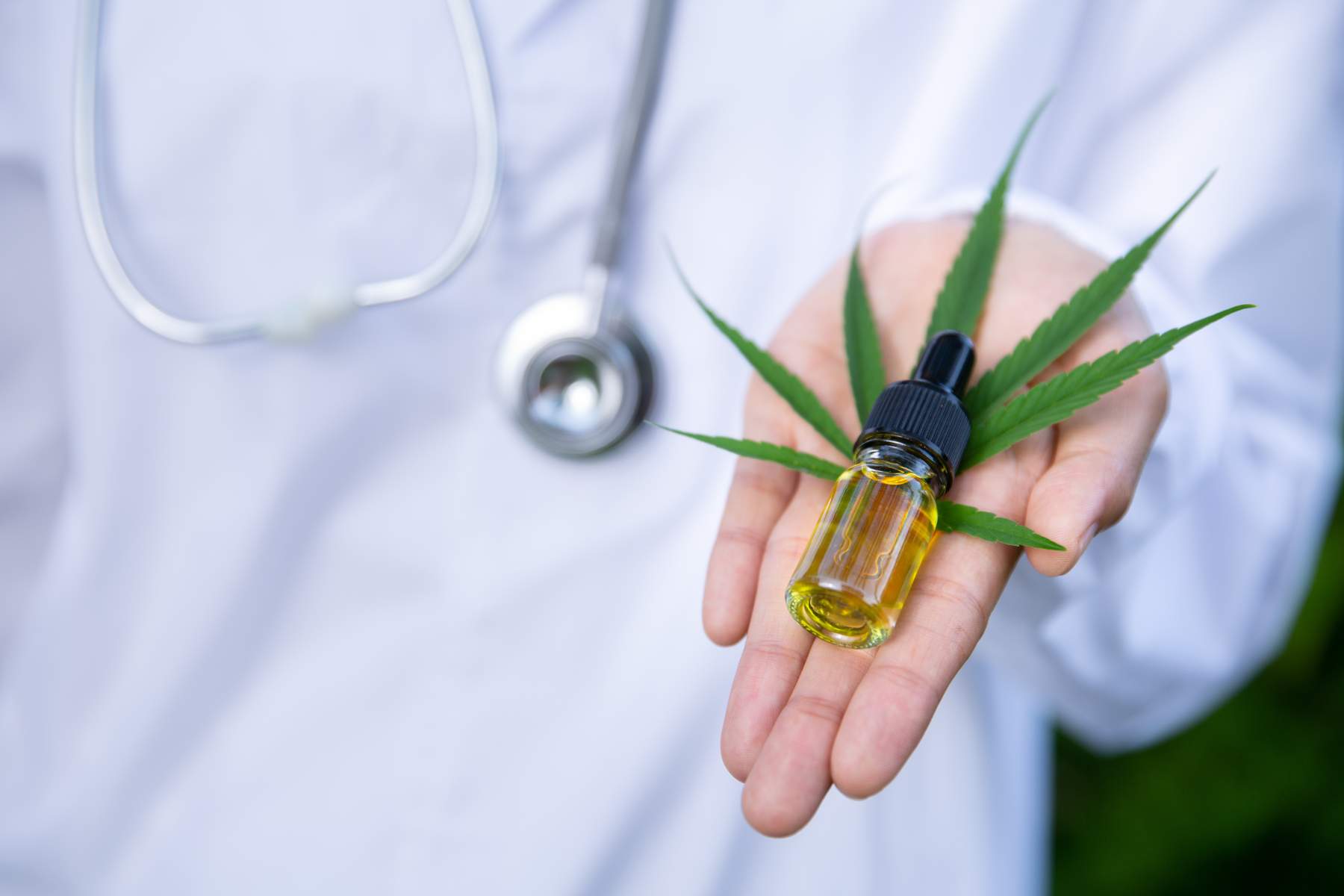 Doctor holding CBD oil bottle with cannabis leaf